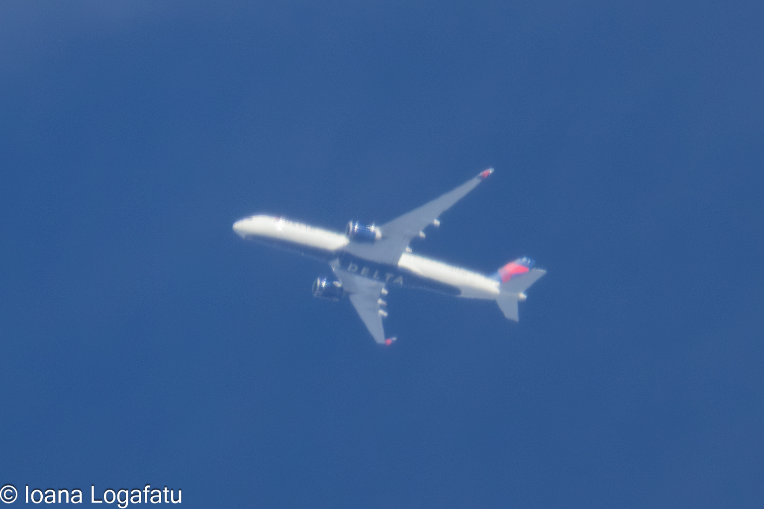 Airplane soaring high across a clear blue sky